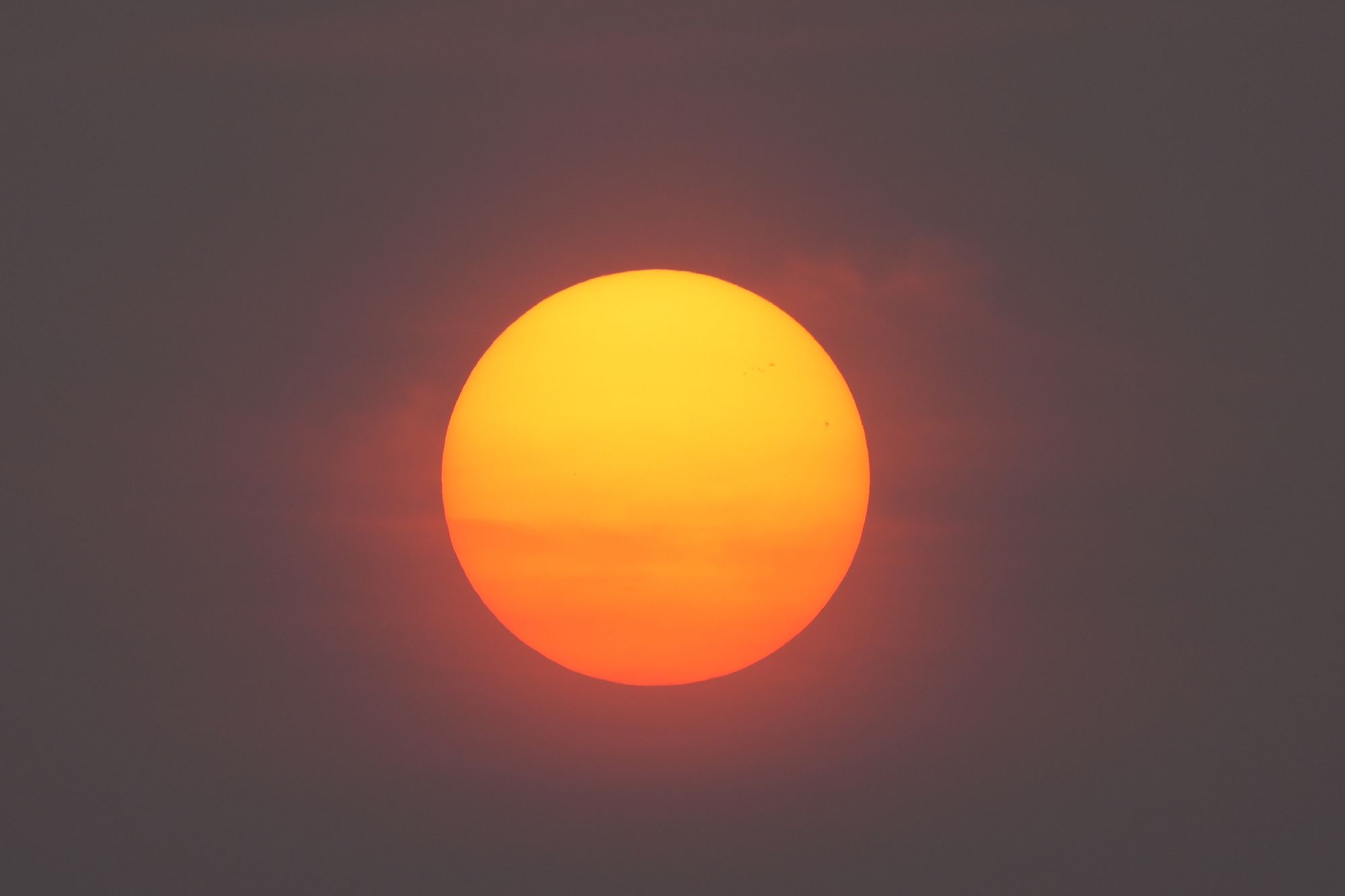 Sol difuminado detrás de una capa de humo sobre un paisaje seco al atardecer