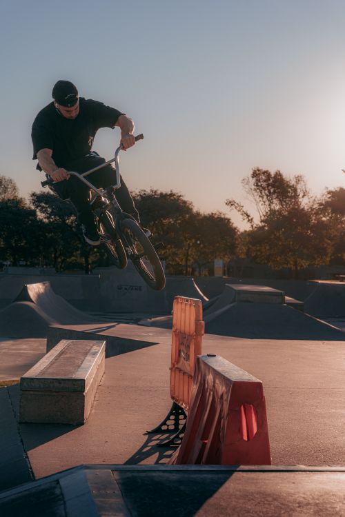 Free A BMX rider skillfully executing an air trick at a skate park during sunset. Stock Photo