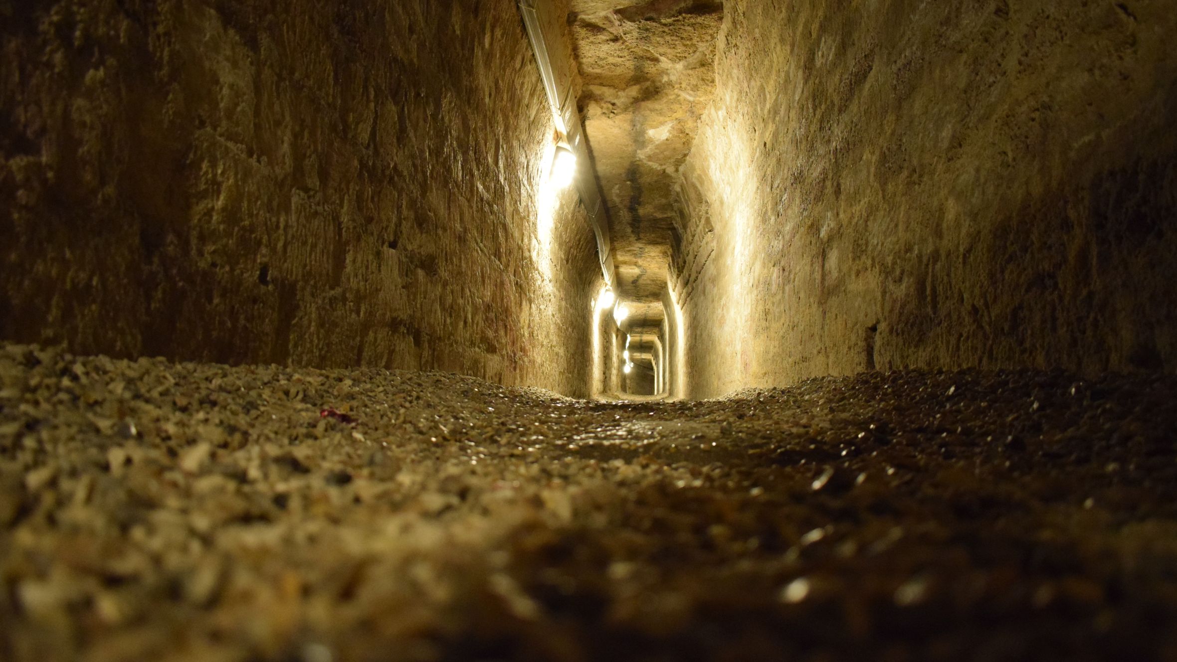 Moody stone tunnel in the Paris Catacombs, dimly lit and mysterious.