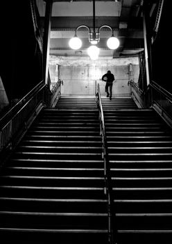 A solitary figure ascends illuminated stairs in a Paris subway, capturing a moody urban scene.