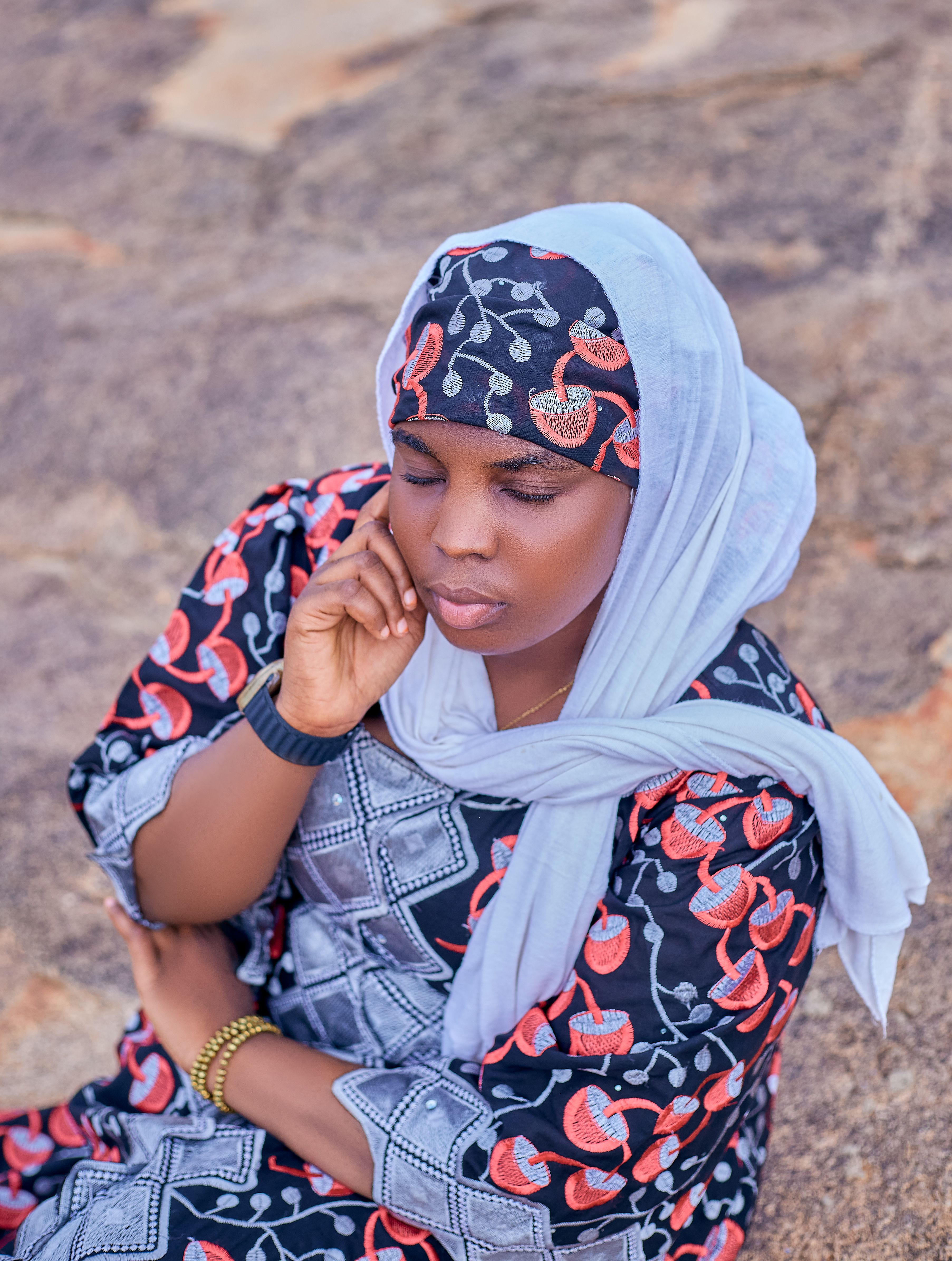 Elegant woman in traditional dress outdoors, deep in thought.