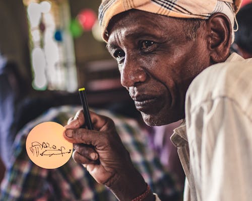 Selective Focus Photography of Man Holding Marker and Round Paper