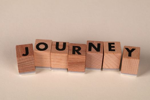 Wooden blocks arranged to spell 'Journey' on a table, symbolizing adventure or progress.
