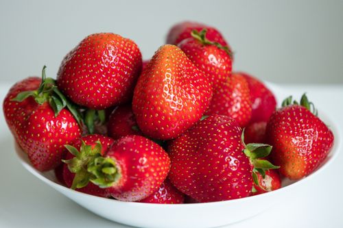 Free A vibrant close-up of fresh red strawberries in a white bowl, perfect for healthy eating representation. Stock Photo