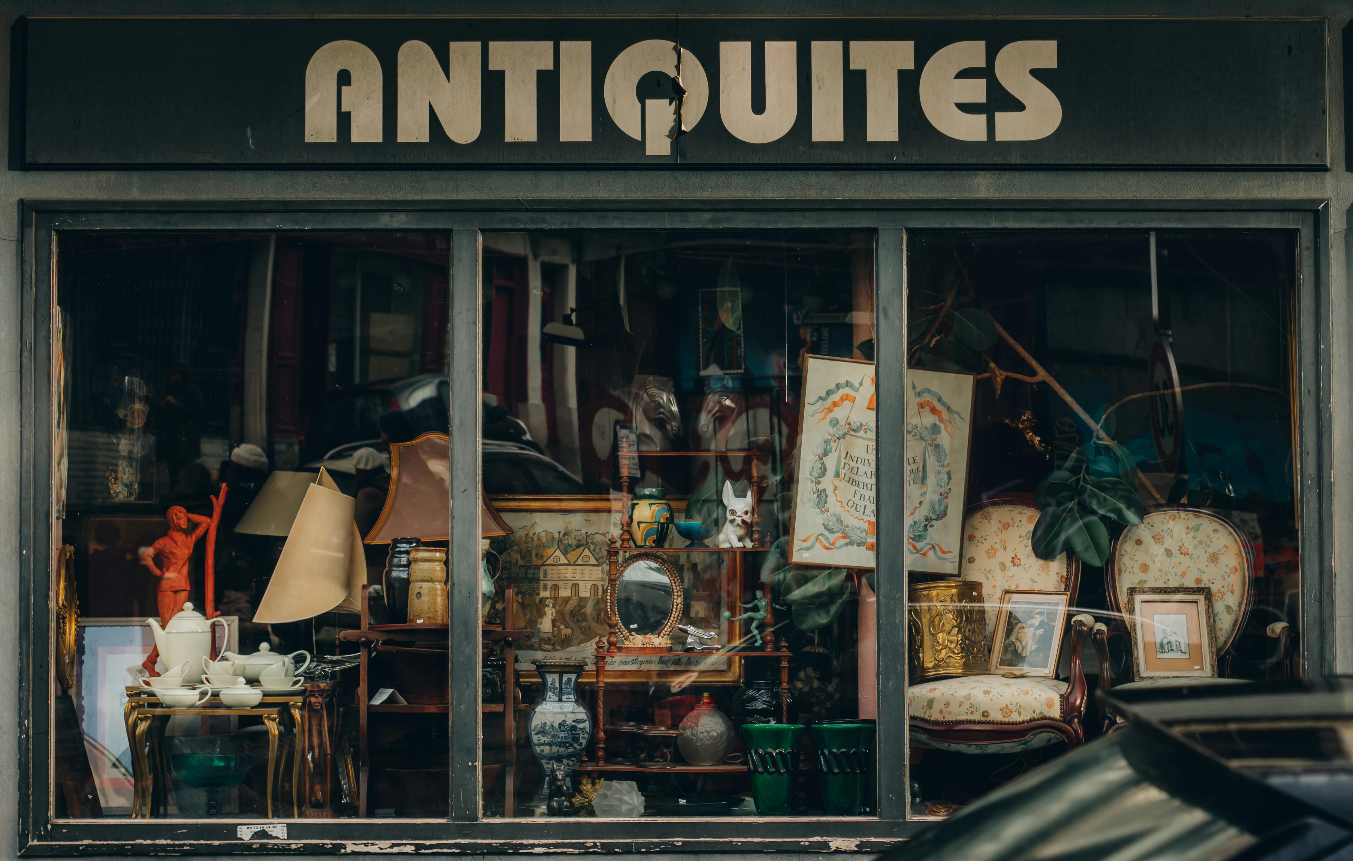 Explore a quaint Parisian antique shop with an elegant window display showcasing vintage treasures.
