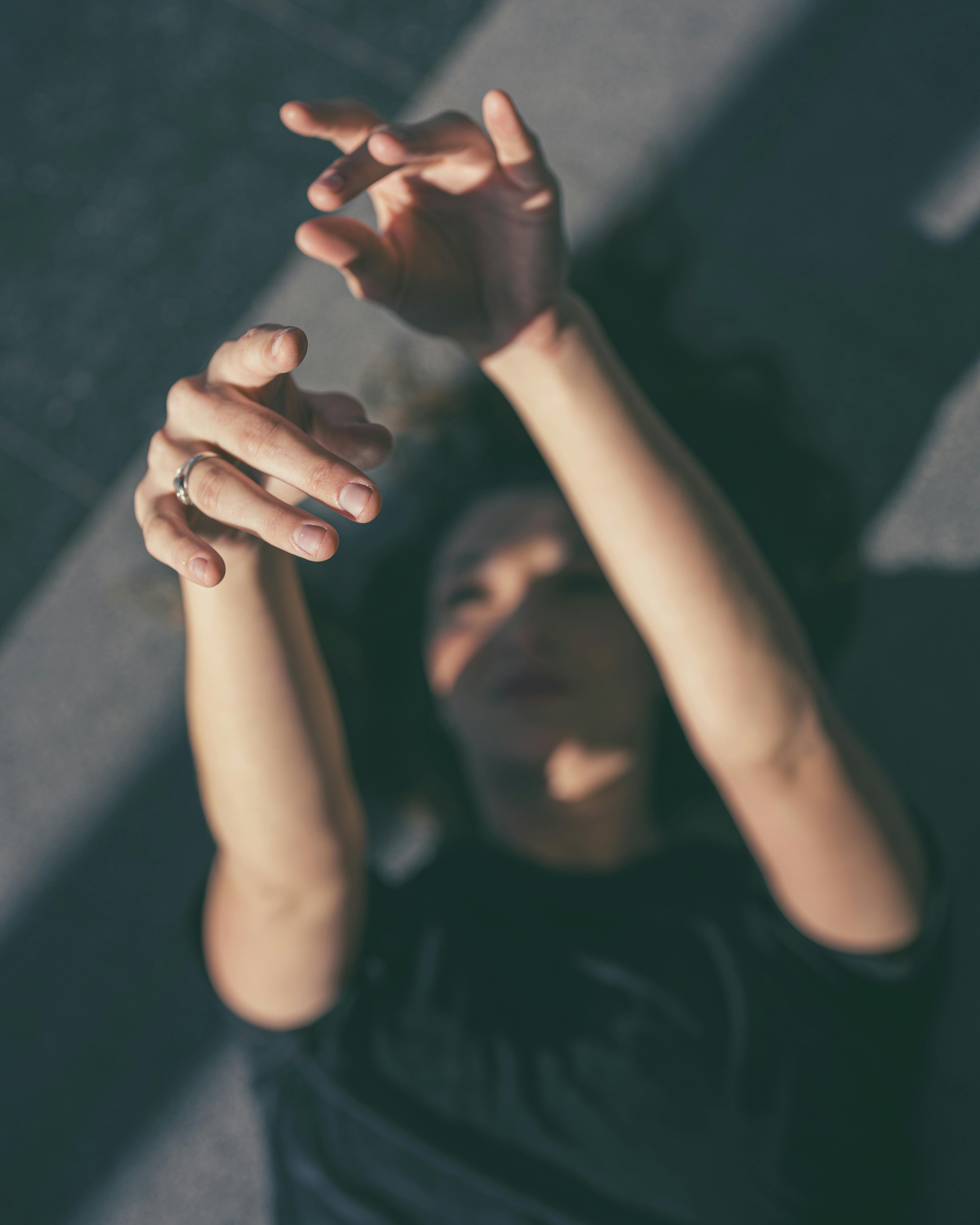 бесплатная Человек тянет руки к солнечному свету, создавая драматические тени. Стоковое фото