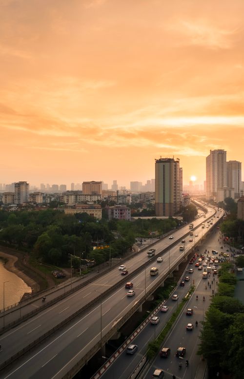 Free A vibrant city highway with flowing traffic at sunset, framed by skyscrapers and a stunning sky. Stock Photo