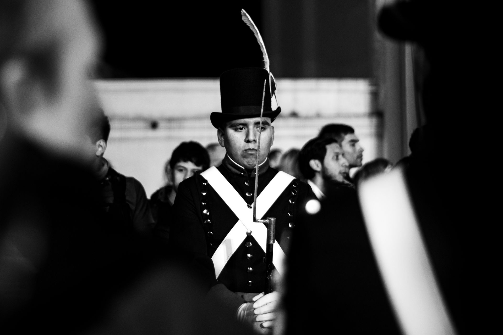 A striking black and white portrait of a soldier in historical attire at a street event.