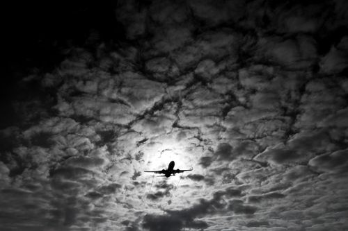 Free A striking black and white image of an airplane silhouette against a textured cloudy sky in Buenos Aires. Stock Photo