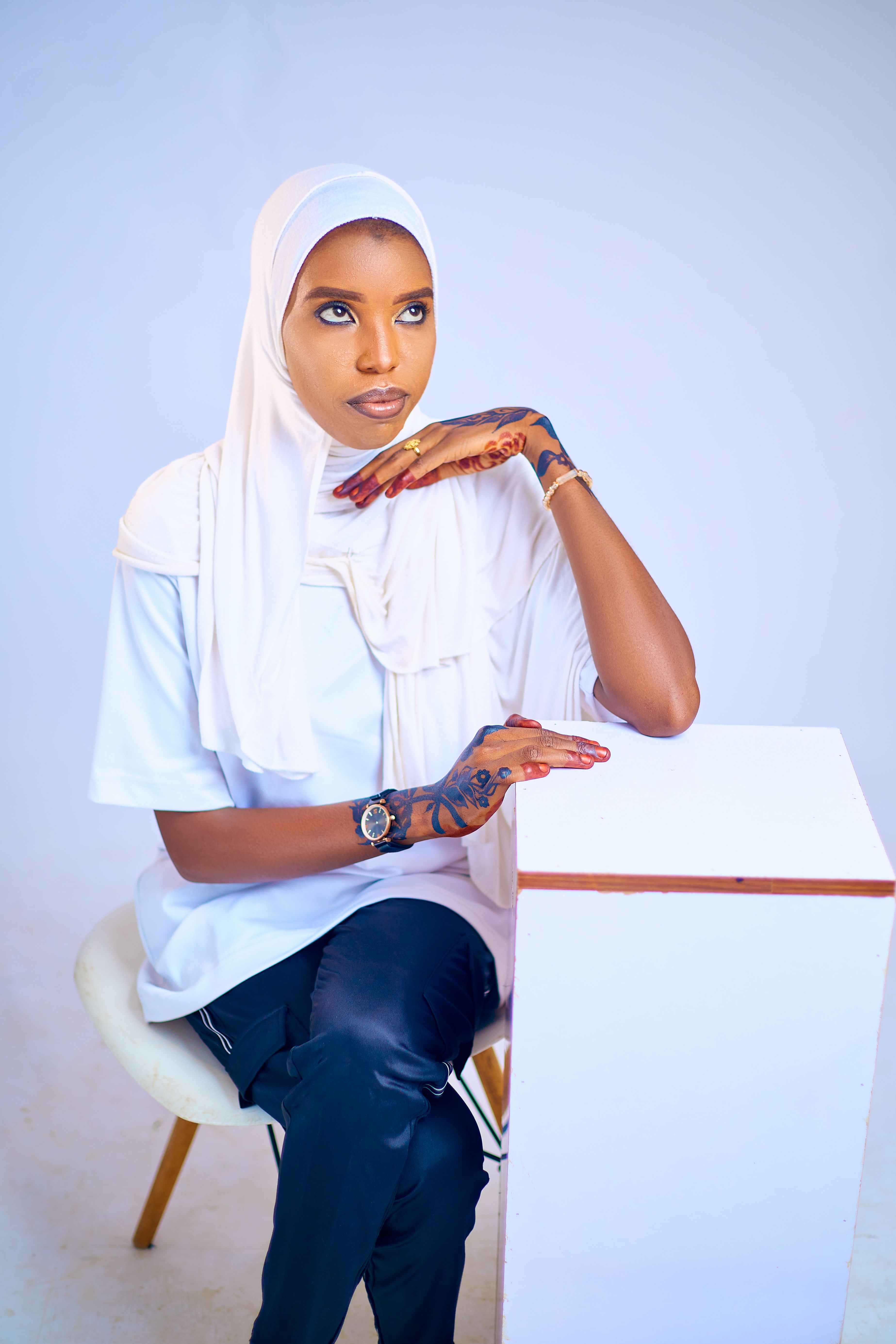 Graceful woman wearing a white hijab with intricate henna designs on her hands.