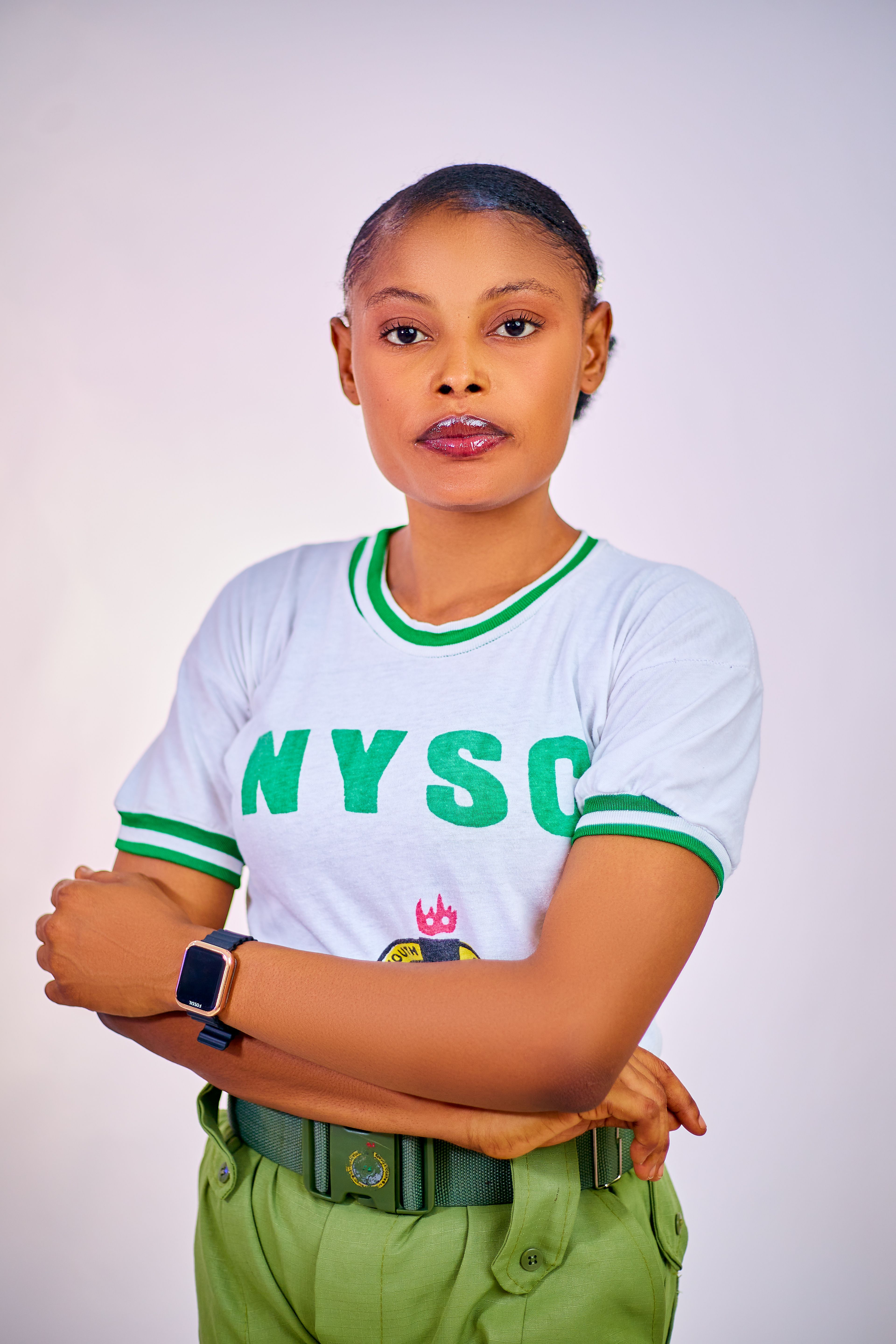 Confident young woman in NYSC uniform with arms crossed, vivid and clear portrait.
