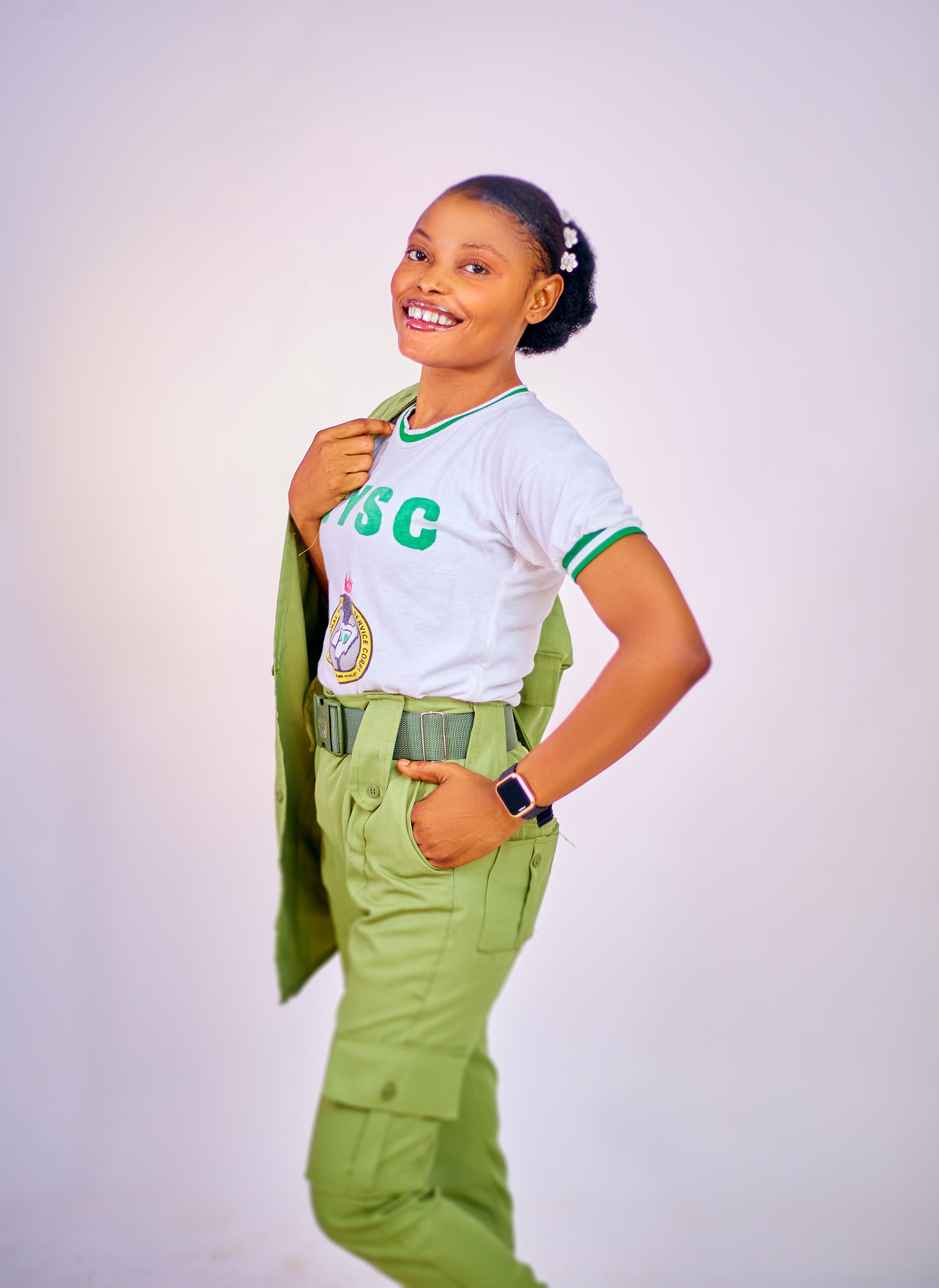 Confident young woman in uniform, smiling brightly against a neutral background.