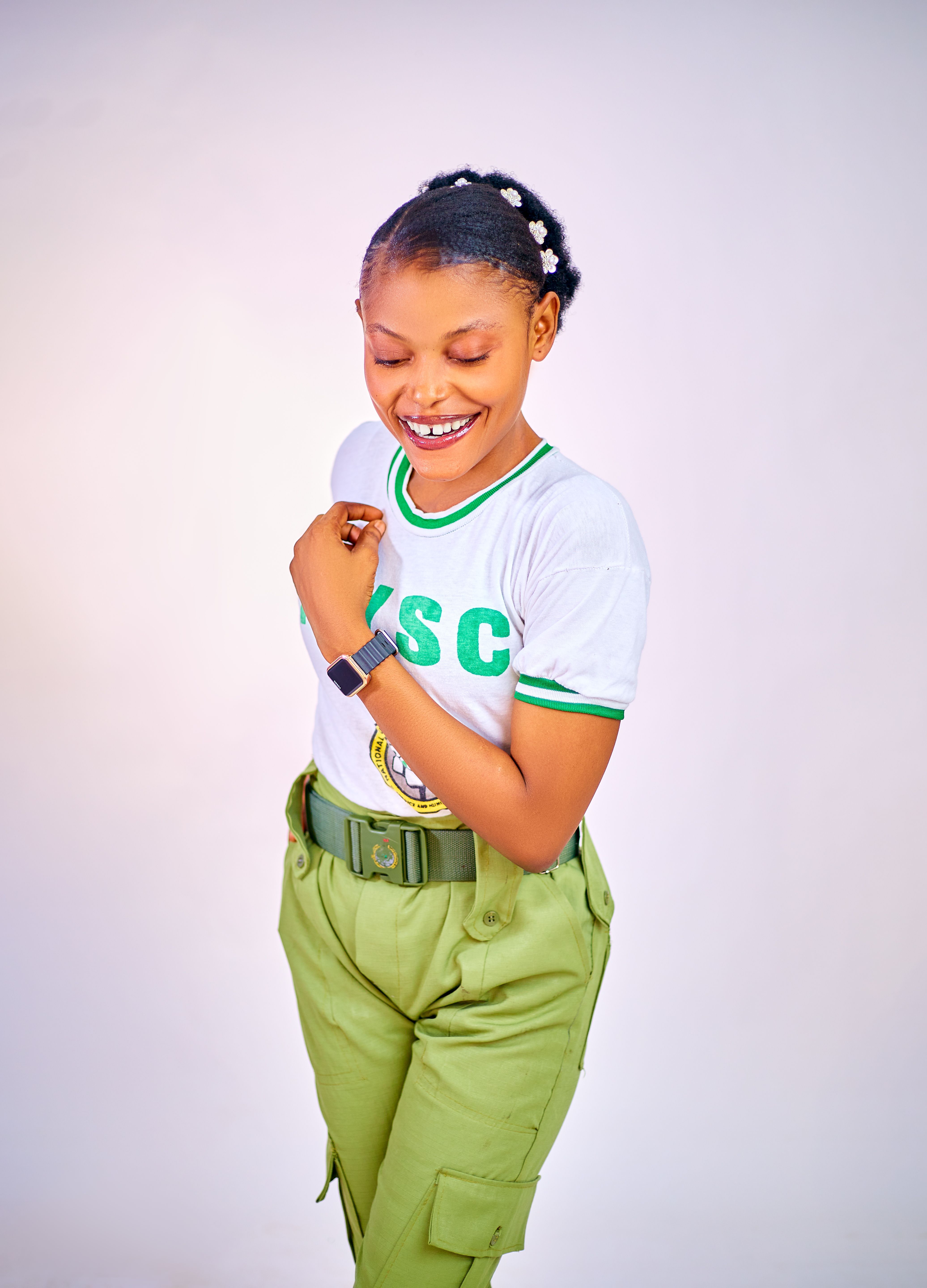 Young woman smiling, wearing uniform with green details, against white background.