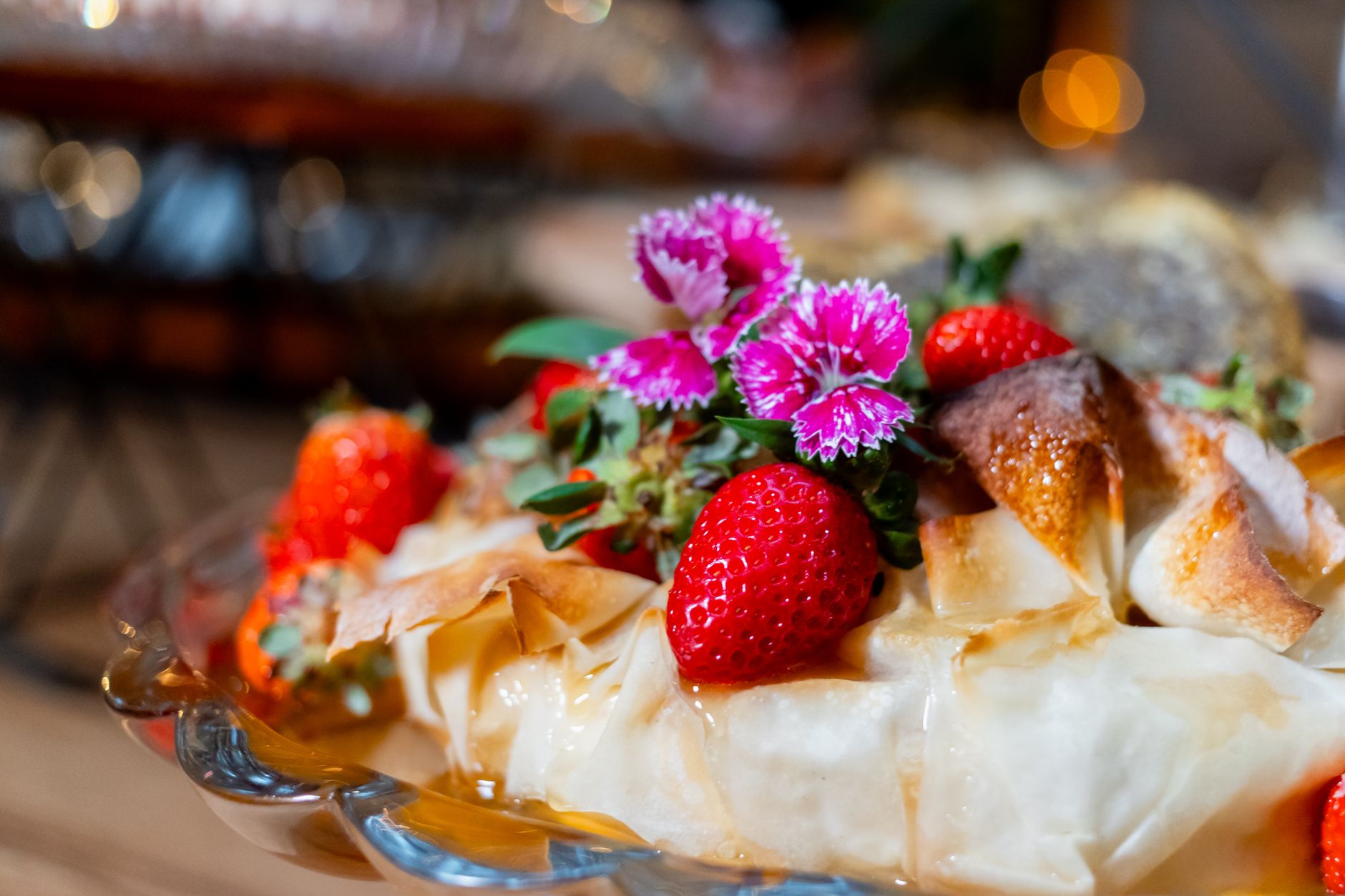 Close-up of a pastry topped with fresh strawberries and purple flowers