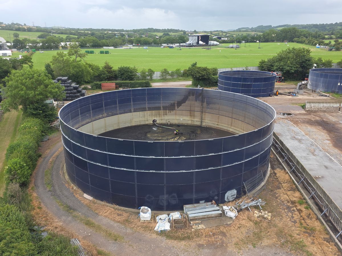 Aerial photo showcasing large industrial water tanks amidst lush countryside landscape under cloudy sky. Illustrative editorial photograph.