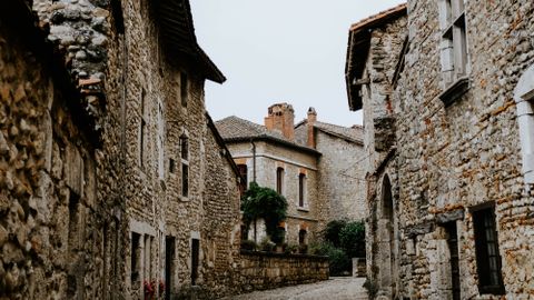 A serene cobblestone alley winds through a historic stone-built town, capturing traditional architecture.