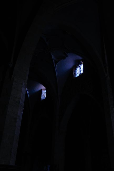 A dark gothic church interior with soft light filtering through windows, creating an eerie atmosphere.