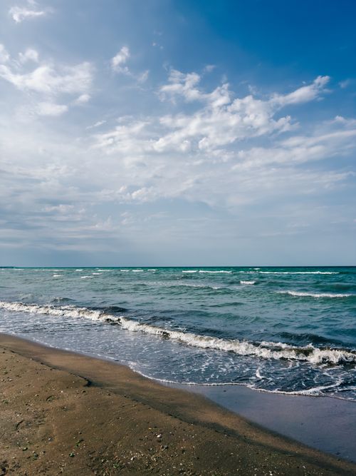 Free Serene view of the Black Sea waves lapping against the sandy beach under a bright blue sky in Baku, Azerbaijan. Stock Photo