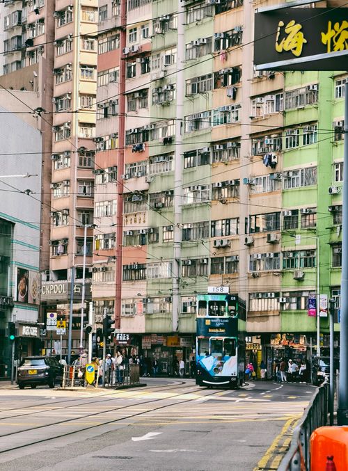 Free Iconic double-decker tram passing through bustling Hong Kong urban streets during the day. Stock Photo
