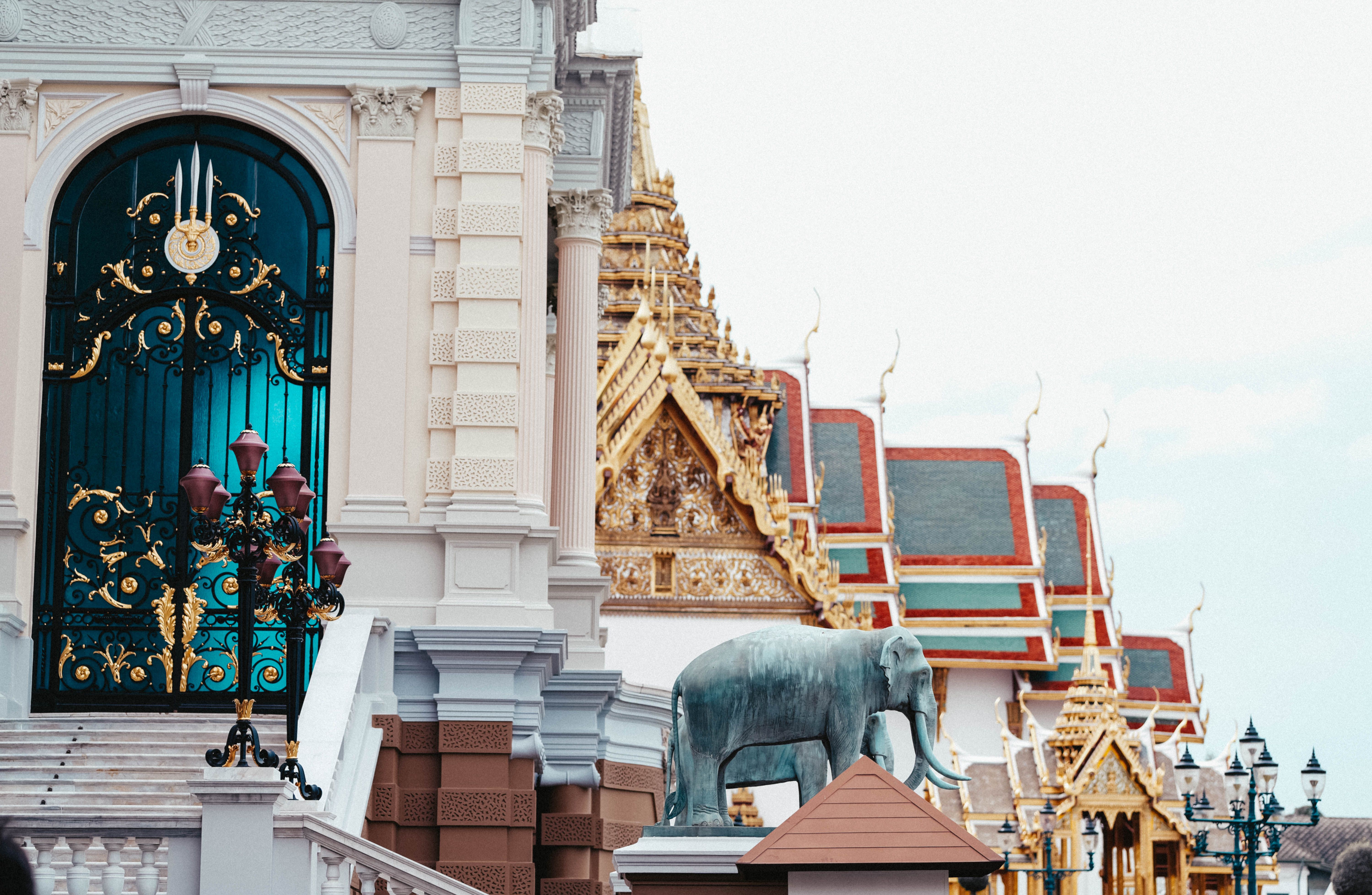 A stunning view of ornate Thai architecture featuring an elephant statue and intricate gates.