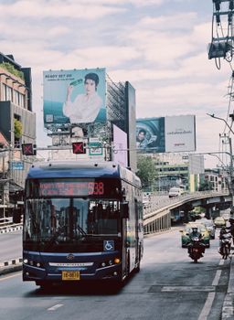 Busy city street scene with a bus and large billboards under a clear sky.