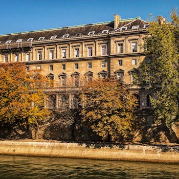 Historic Parisian facade with autumn foliage by the Seine River, showcasing classic architecture.