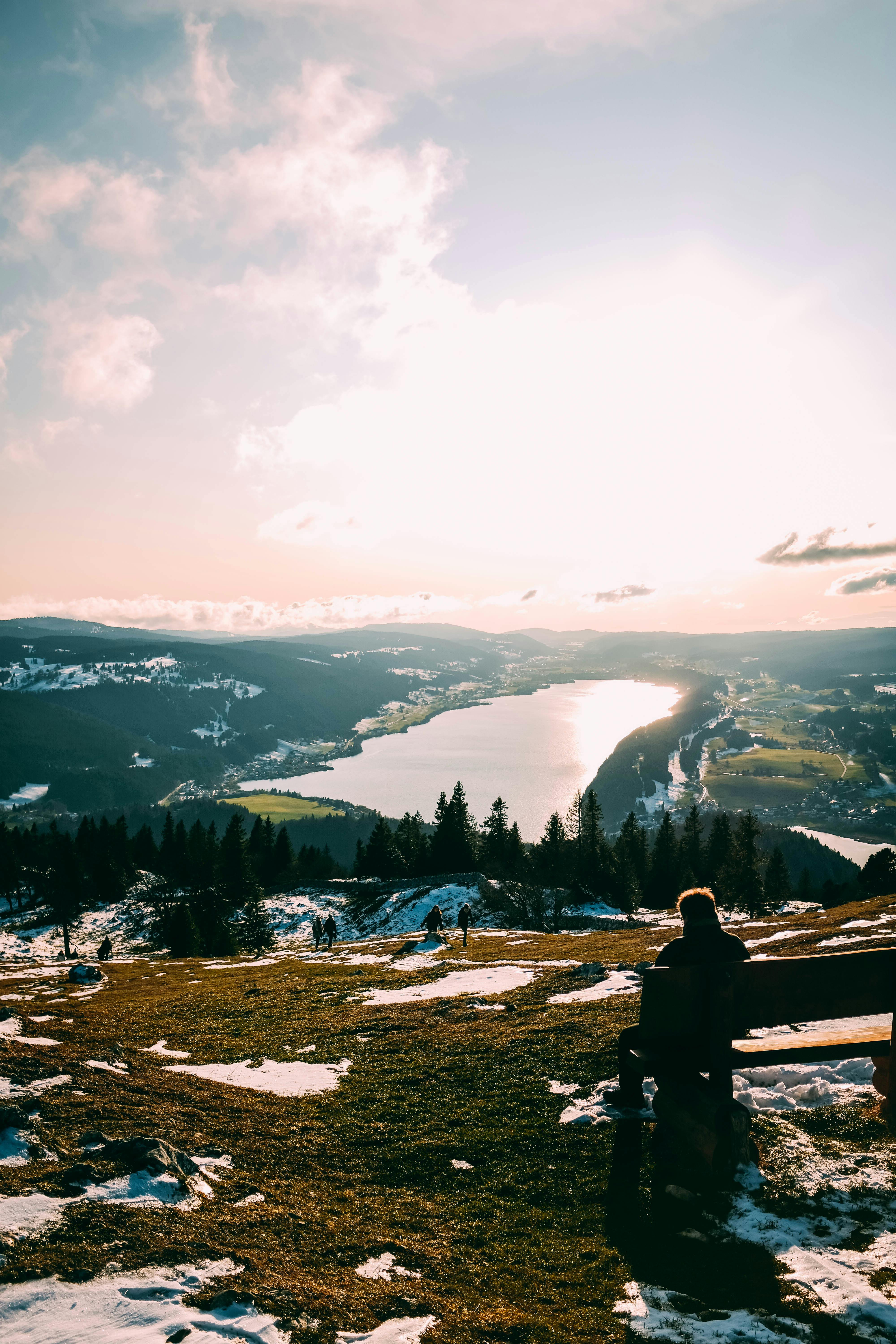 Prescription Goggle Inserts - Person enjoying a tranquil view of a lake and mountain during sunset, surrounded by snow and nature.