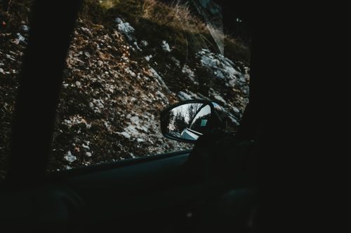 Free Captivating view of a forest landscape reflecting in a car's side mirror, depicting travel and adventure. Stock Photo