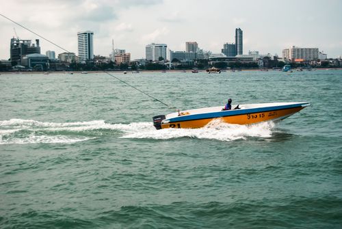 Free Dynamic shot of a speedboat in Pattaya Bay, Thailand, with a vibrant cityscape backdrop. Stock Photo