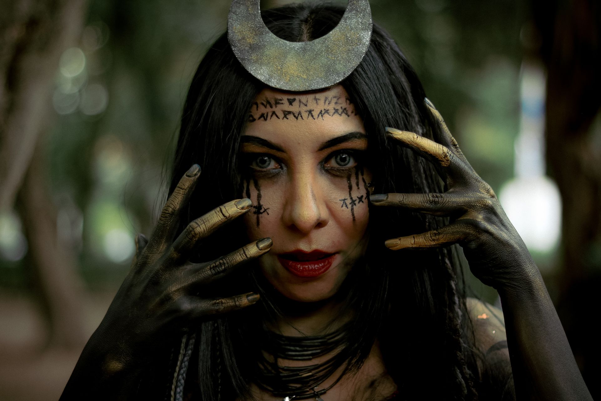 Captivating portrait of a woman with runes and crescent moon headpiece in dark forest.