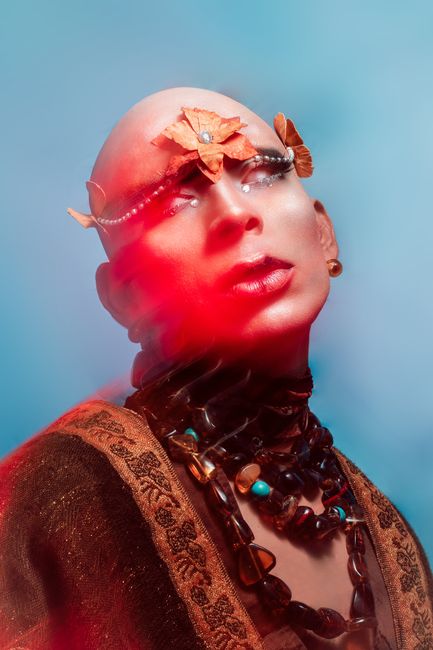 Ethereal fashion portrait showcasing bold makeup and accessories in a studio setting.