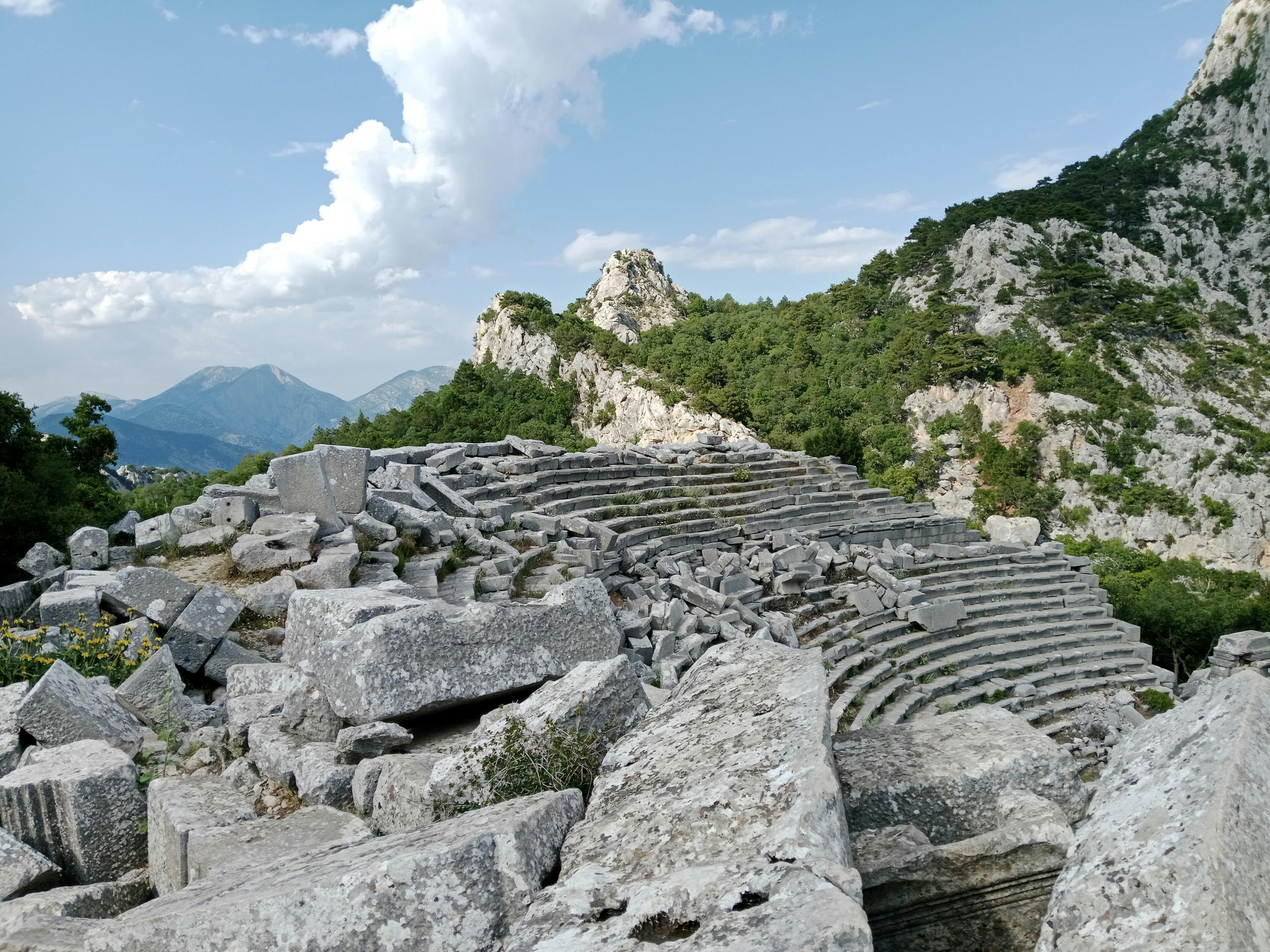Kostnadsfria Utforska de antika amfiteaterruinerna i Termessos, inbäddade i det bergiga landskapet under en klarblå himmel. Stock foto
