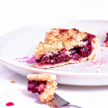 Close-up of a berry pie slice on a white plate with vibrant berry filling.