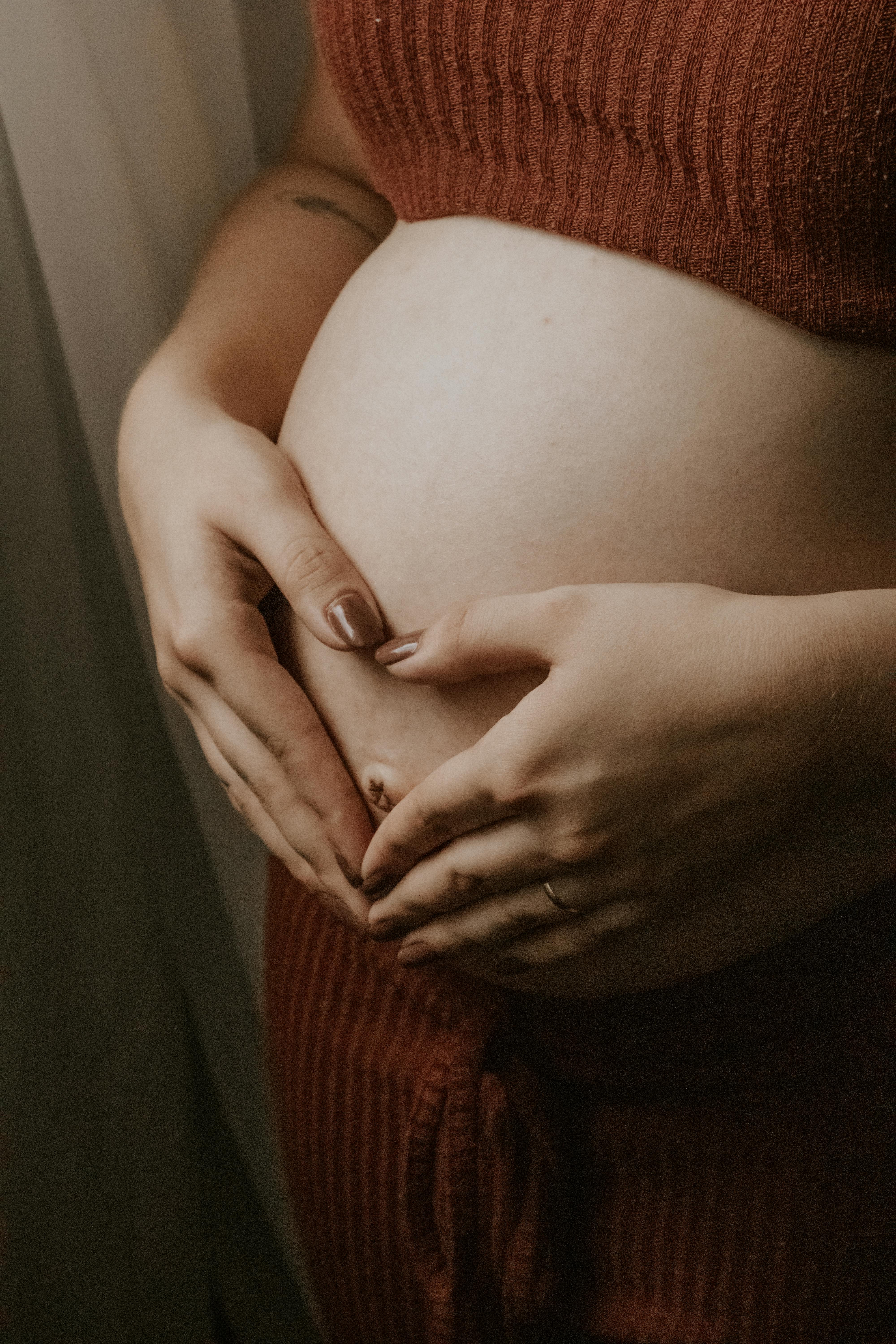 Close-up of a pregnant woman embracing her belly in intimate lighting, symbolizing motherhood.
