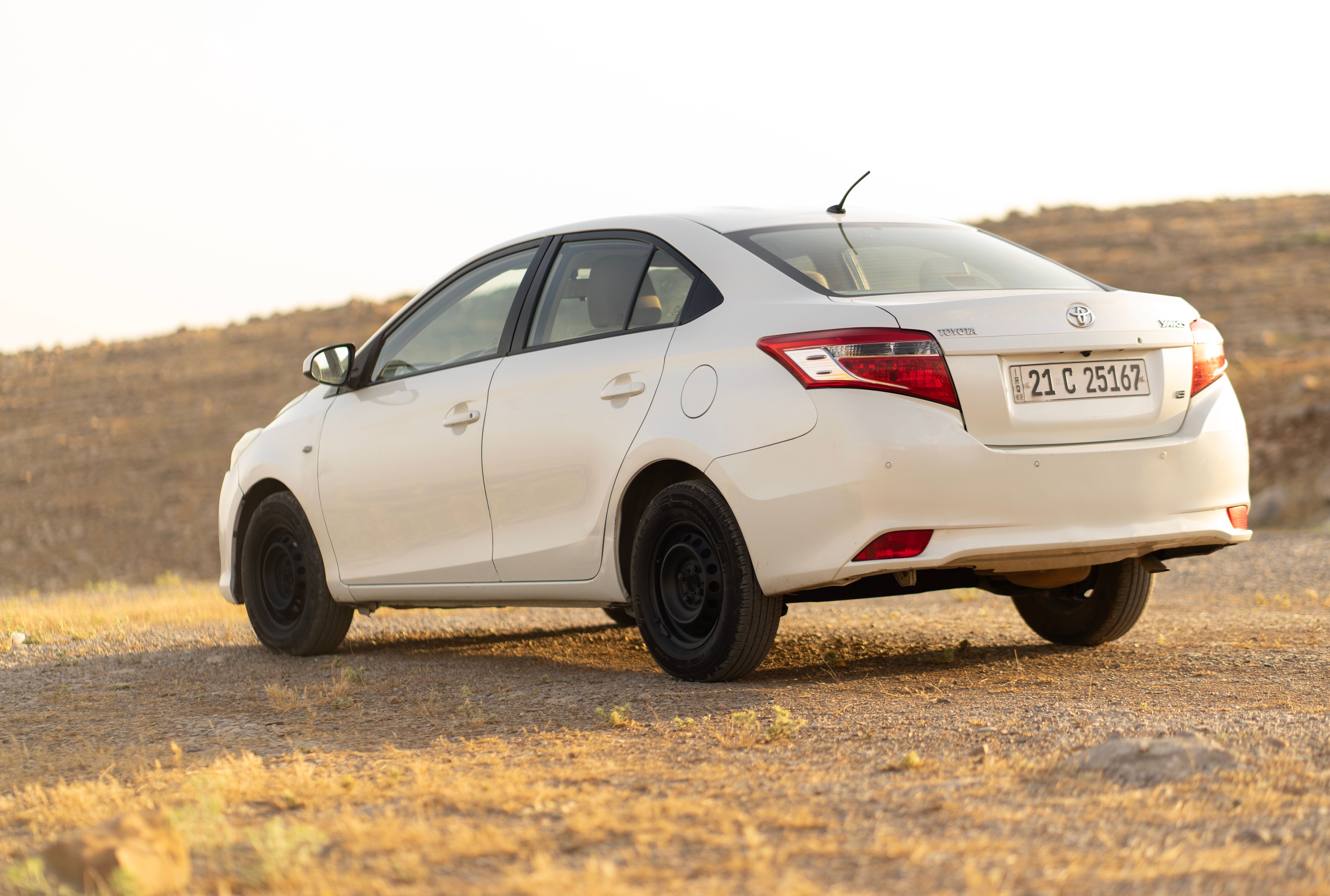 Free A white Toyota Vios parked in a desert landscape during daylight. Stock Photo