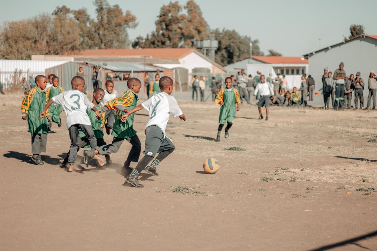 children engaged in a lively soccer game on a sunny day in south afric