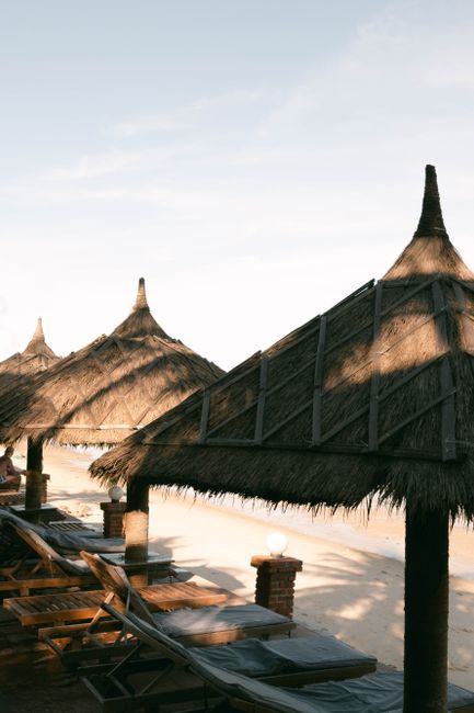 Serene beach scene with thatched umbrellas and lounge chairs at sunrise, evoking relaxation.