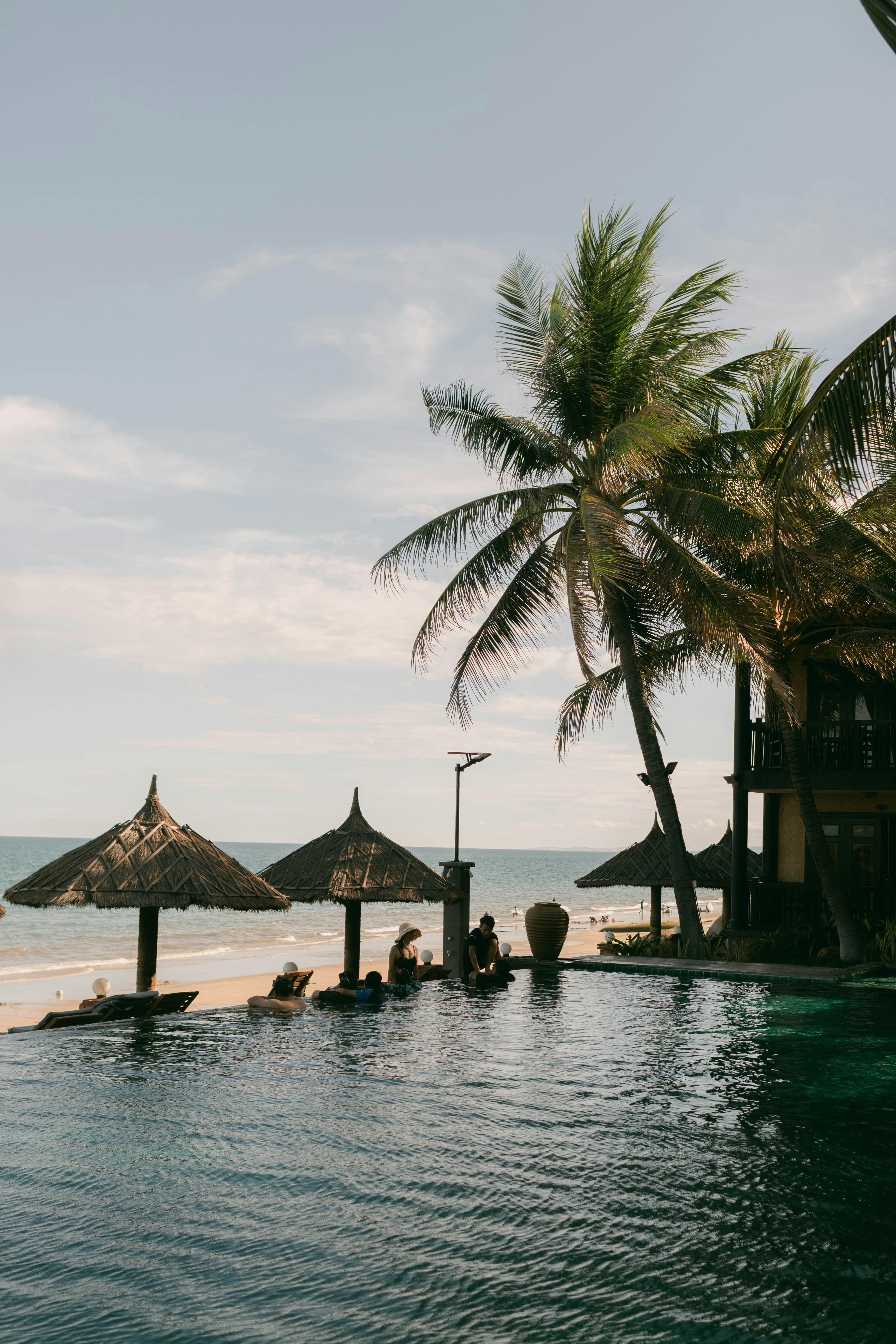 Beachfront infinity pool framed by palm trees at a five-star luxury hotel in Nusa Dua, Bali