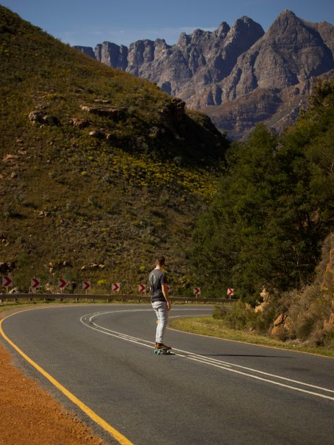 A skateboarder rides down a winding mountain road in Cape Town, South Africa.