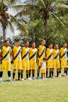 A soccer team in yellow uniforms stands aligned outdoors, ready for play.