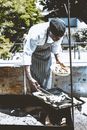 African American male cook in apron standing near railing and grilling food in sunny summer day