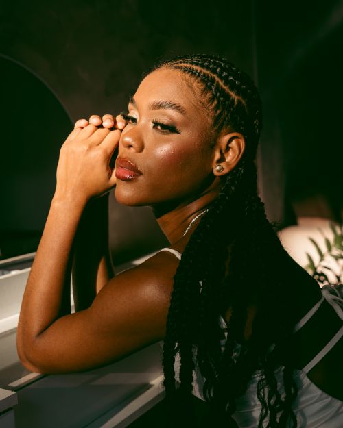 Free Striking portrait of a woman with braids, leaning on a white piano under dramatic lighting. Stock Photo