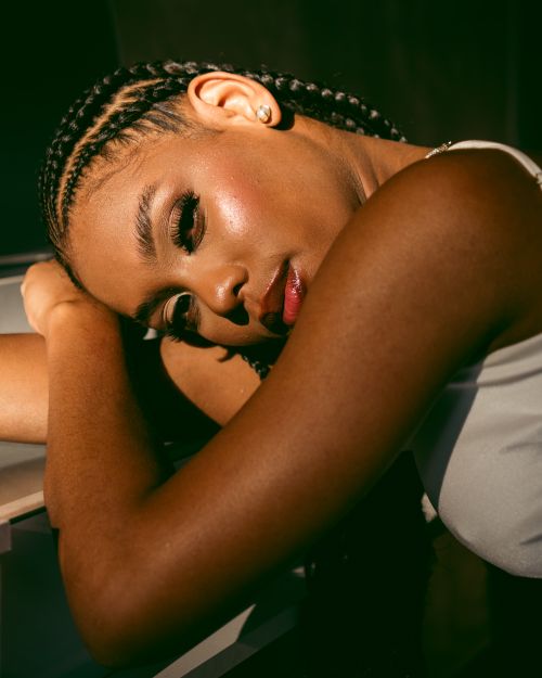 Free Elegant portrait of a woman with braided hair resting her head, captured in warm sunlight indoors. Stock Photo