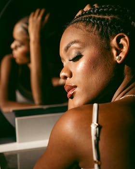 Close-up portrait of a woman with braids gazing into a mirror reflecting elegance and confidence.