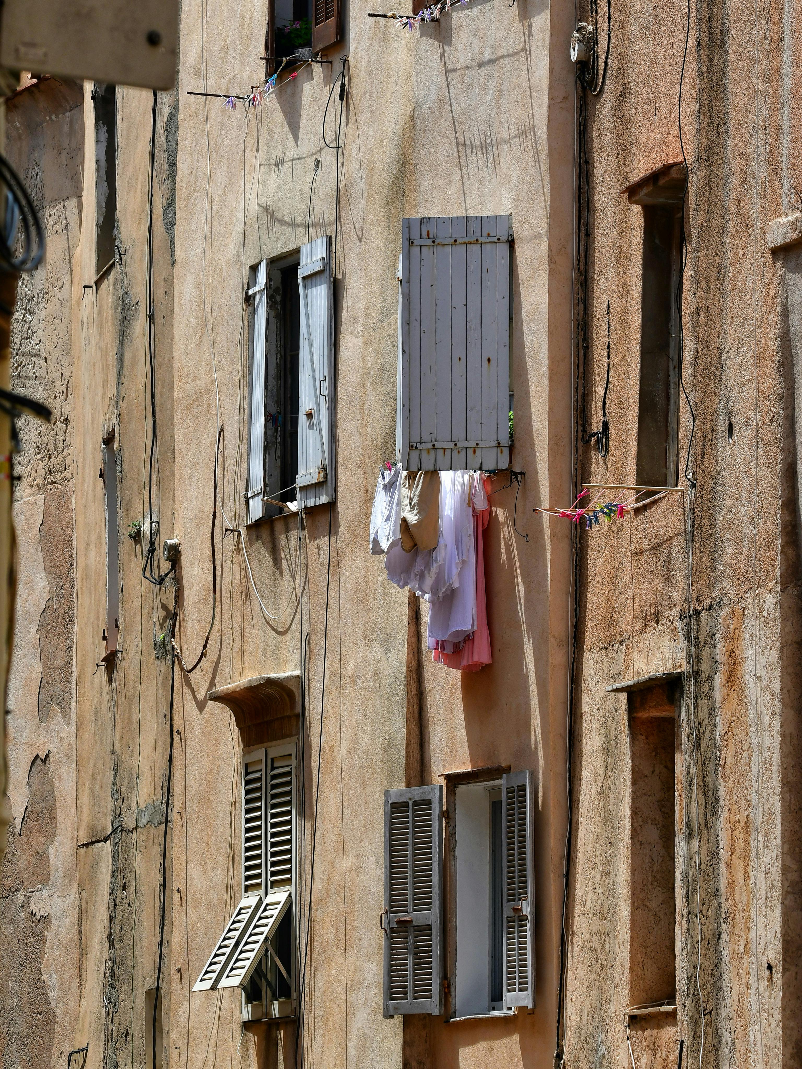 Weathered Mediterranean building facade with colorful laundry hung out to dry.