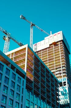 Dynamic view of skyscraper construction with cranes in an urban city setting.