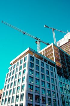 High-rise building under construction with cranes against a clear sky.