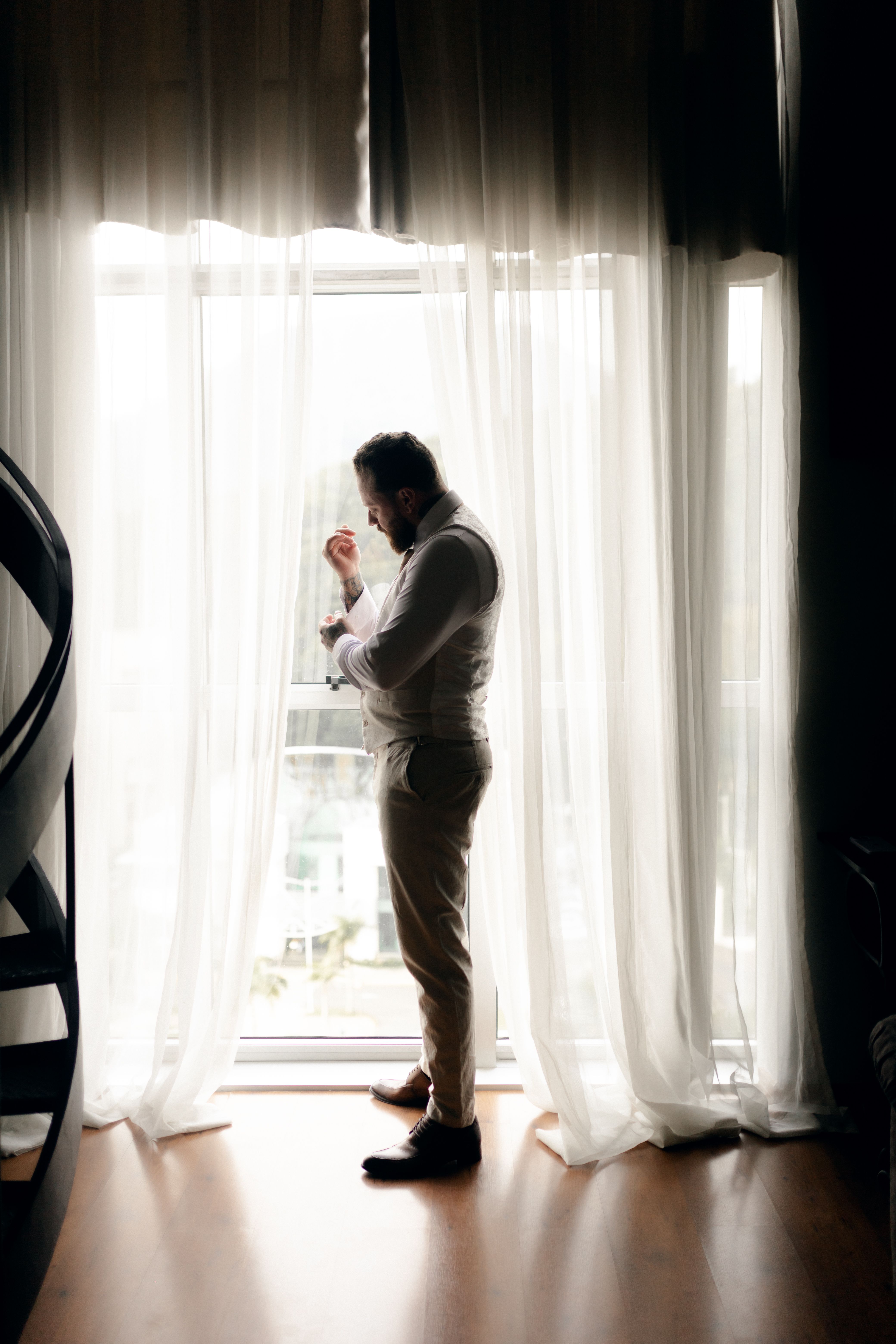 A man adjusting his suit in soft window light