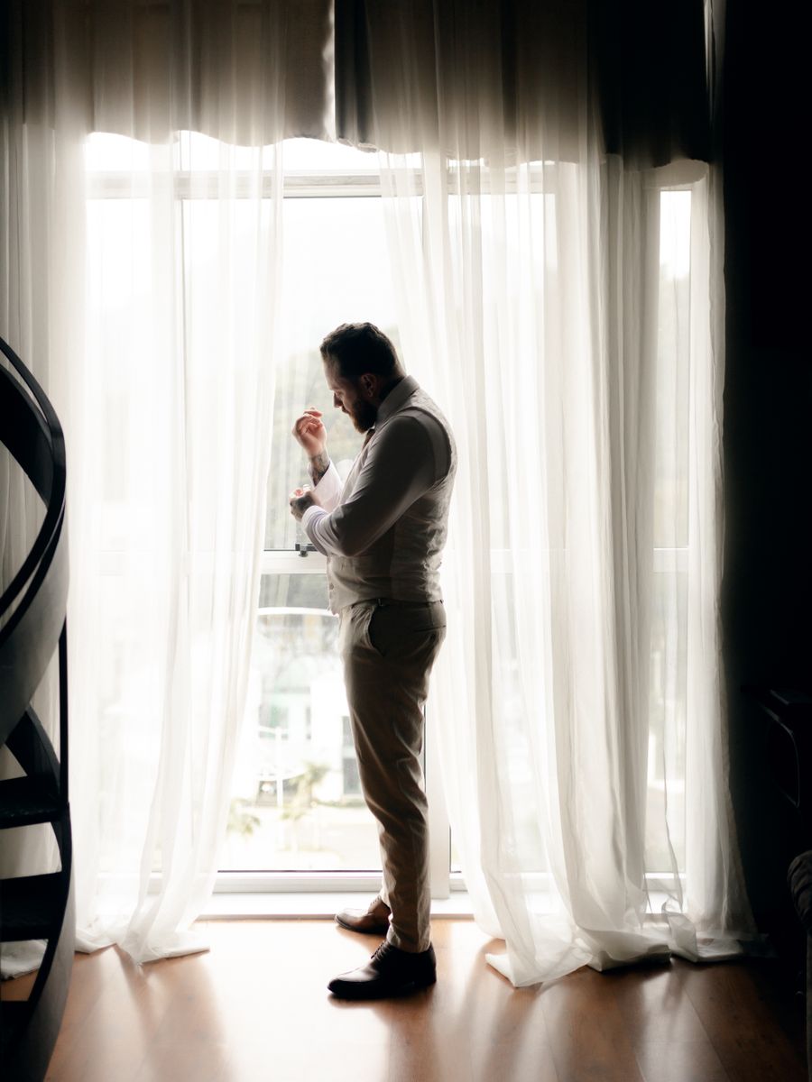 A man adjusting his suit in soft window light