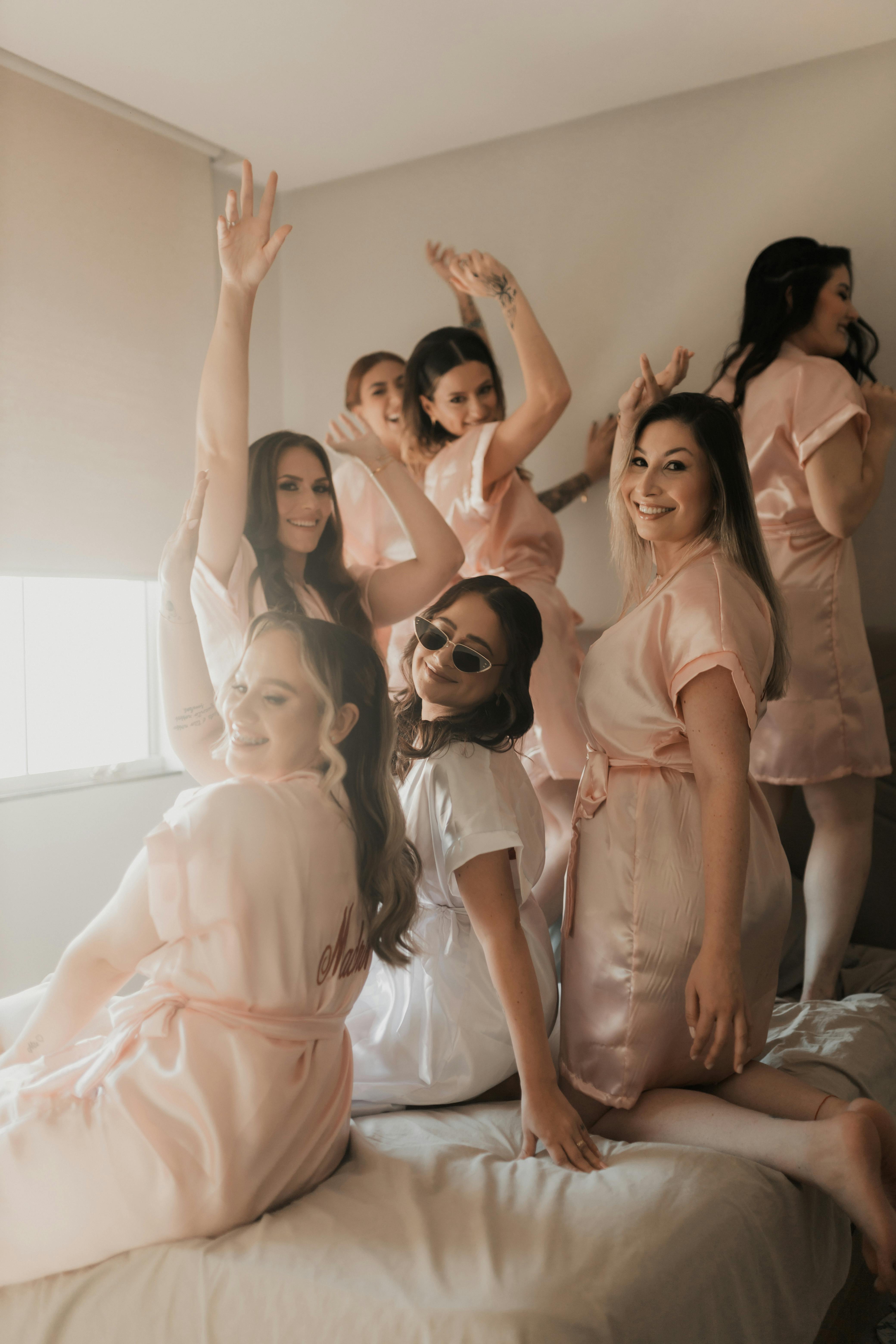 Joyful bridal party in satin robes posing indoors, capturing a fun pre-wedding moment.